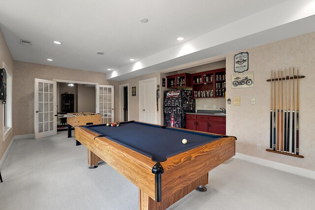 recreation room with baseboards, wet bar, light carpet, and french doors