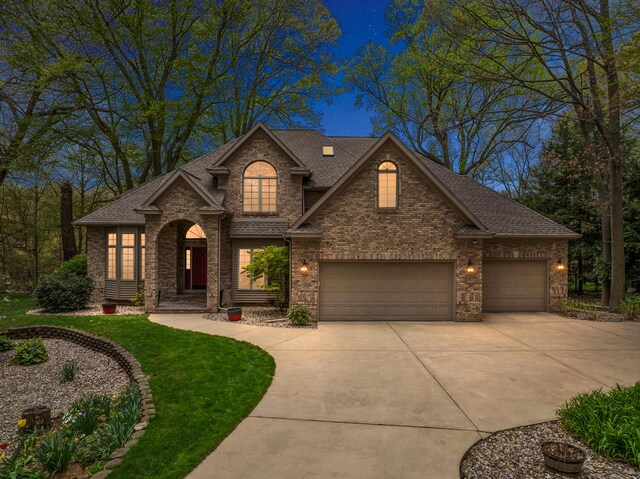 view of front of house featuring brick siding, driveway, and roof with shingles
