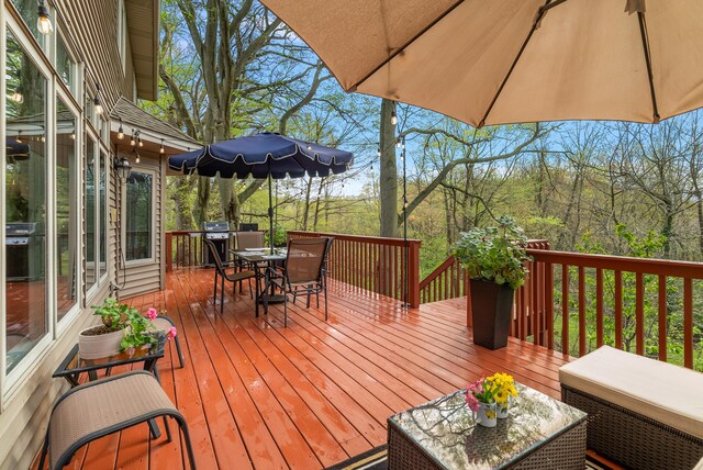 wooden terrace with outdoor dining area and grilling area