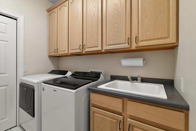 clothes washing area featuring cabinet space, a sink, and washer and clothes dryer
