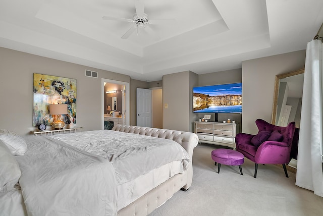 bedroom with visible vents, ceiling fan, a tray ceiling, and light carpet