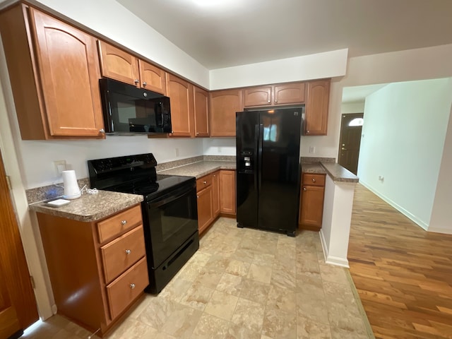 kitchen featuring baseboards, brown cabinetry, and black appliances