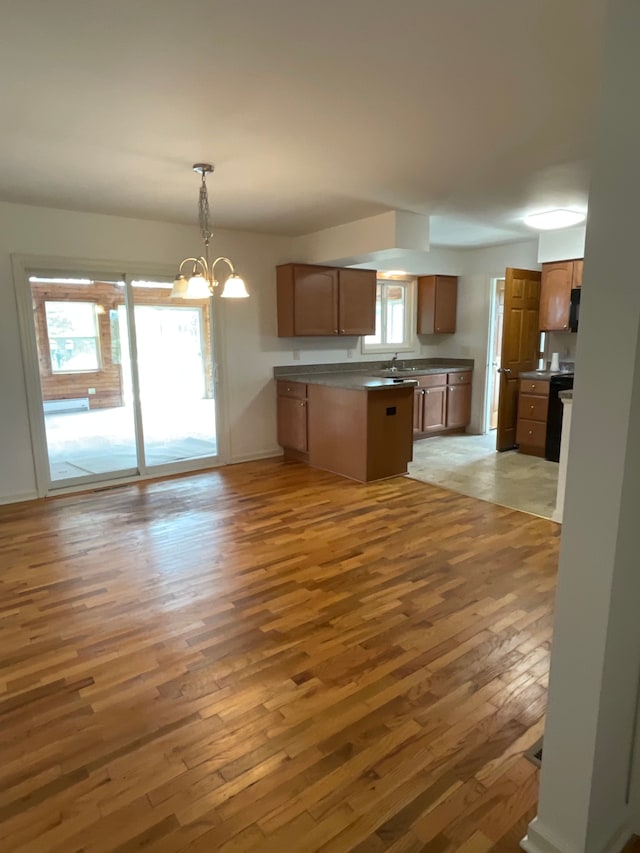 kitchen featuring a peninsula, a notable chandelier, plenty of natural light, and light wood-style flooring