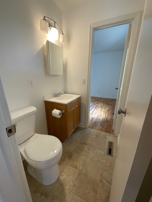 bathroom featuring vanity, toilet, and visible vents