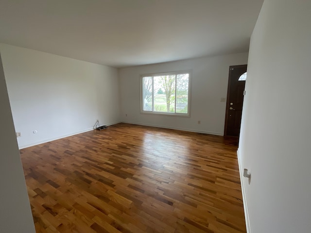 unfurnished room with baseboards and wood finished floors