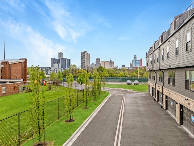 1049 Hampton Cir Unit 44, Detroit, MI 48207 - surrounding community featuring fence, an attached garage, driveway, a view of city, and a lawn