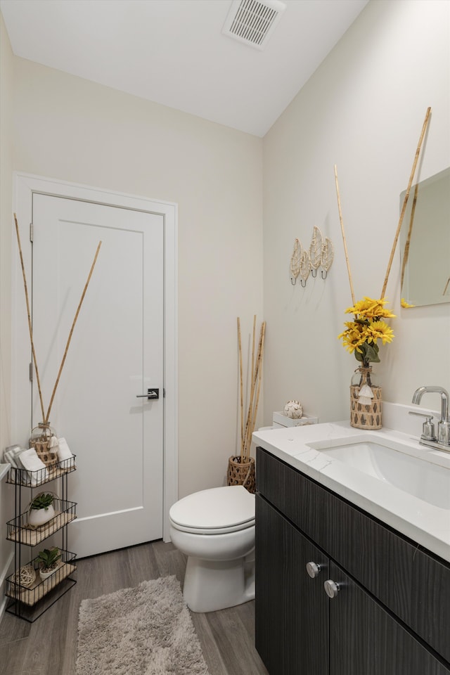 1049 Hampton Cir Unit 44, Detroit, MI 48207 - half bathroom with toilet, visible vents, wood finished floors, and vanity