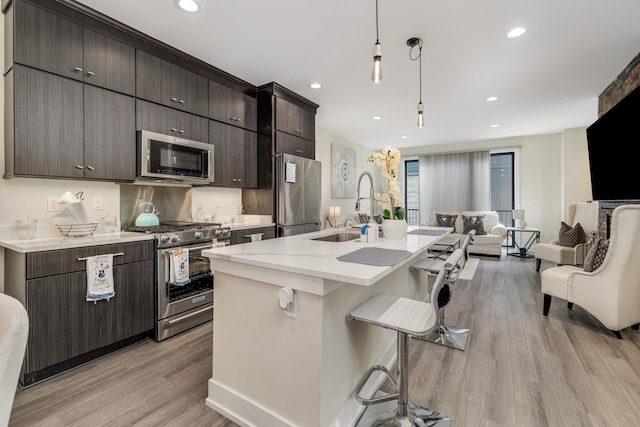 1049 Hampton Cir Unit 44, Detroit, MI 48207 - kitchen with a kitchen bar, a sink, stainless steel appliances, decorative light fixtures, and light wood-style floors