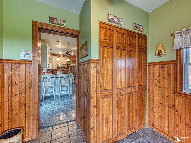 6603 S Stony Creek Rd, Monroe, MI 48162 - hallway featuring a wainscoted wall, stone finish floor, and wood walls