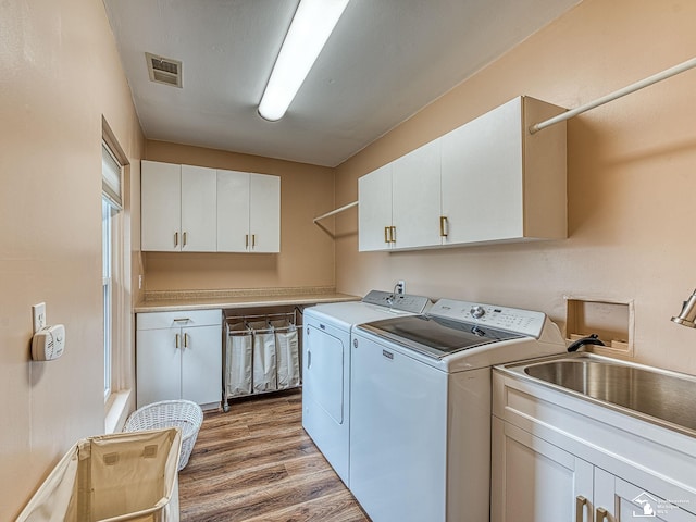 6603 S Stony Creek Rd, Monroe, MI 48162 - laundry area featuring visible vents, light wood-type flooring, washer and clothes dryer, a sink, and cabinet space