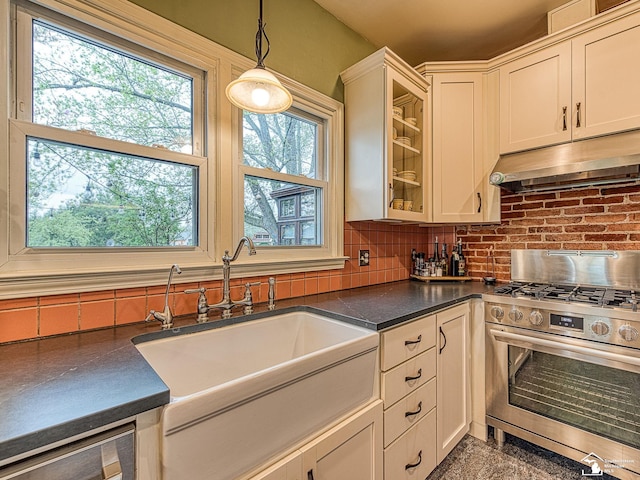6603 S Stony Creek Rd, Monroe, MI 48162 - kitchen featuring dark countertops, under cabinet range hood, tasteful backsplash, stainless steel range with gas stovetop, and a sink