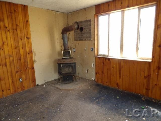 unfurnished living room with wooden walls and a wood stove