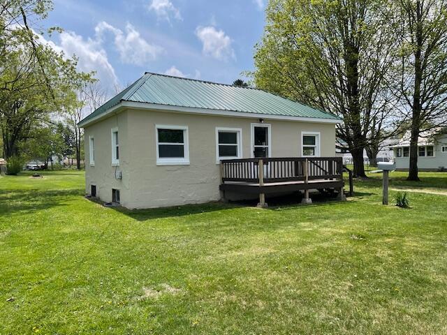 rear view of house with a lawn, metal roof, and a deck
