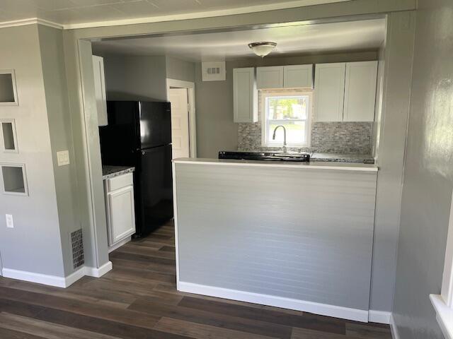 kitchen with baseboards, freestanding refrigerator, dark wood-style flooring, and white cabinets
