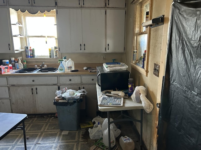 kitchen featuring light countertops, white cabinetry, tile patterned floors, and a sink