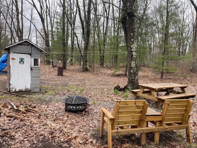 view of yard featuring an outdoor structure, an outdoor fire pit, and a shed