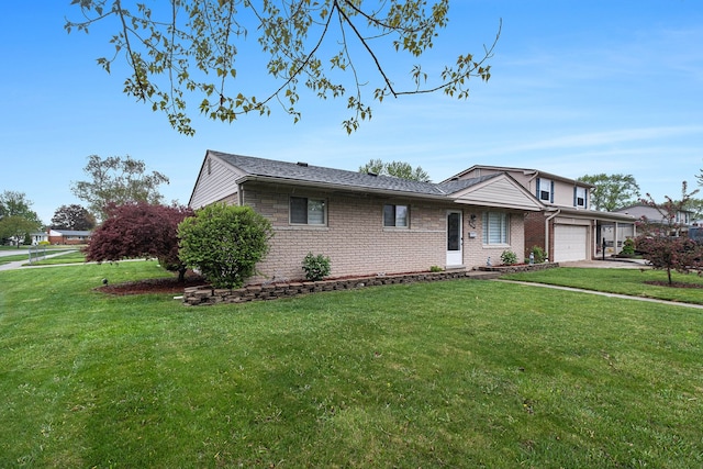 view of front of property featuring an attached garage, a front lawn, and brick siding