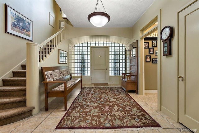 62 Robertson Ct, Clarkston, MI 48346 - entrance foyer featuring stairs, light tile patterned flooring, a textured ceiling, baseboards, and arched walkways