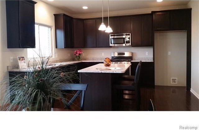 kitchen featuring stainless steel appliances, dark brown cabinetry, recessed lighting, and hanging light fixtures