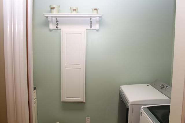 clothes washing area featuring separate washer and dryer and cabinet space