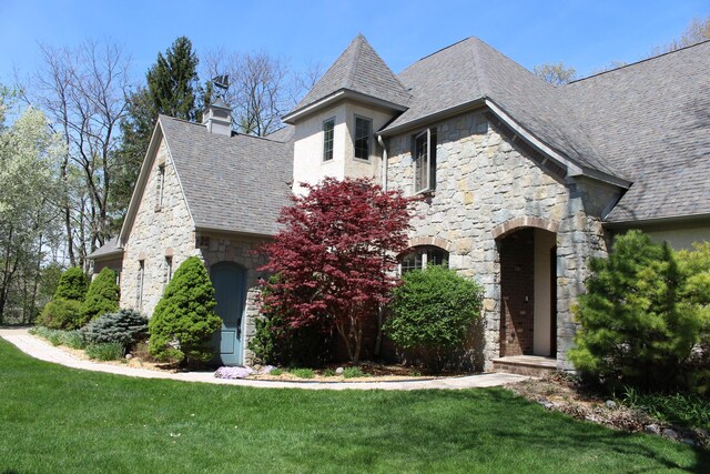 french provincial home featuring a front yard and stone siding
