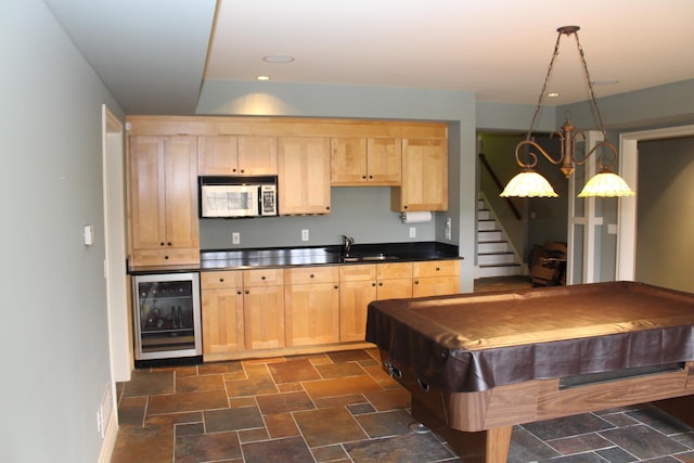 game room with beverage cooler, baseboards, a sink, and stone finish floor