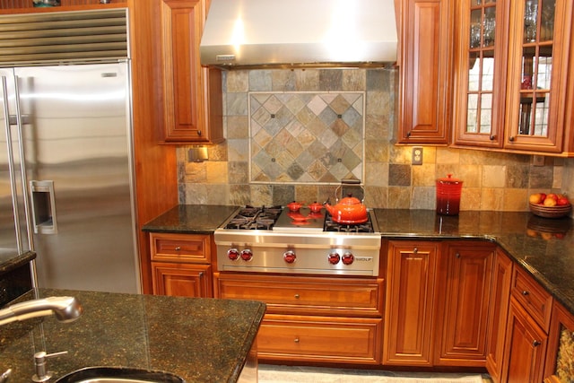 kitchen featuring appliances with stainless steel finishes, decorative backsplash, a sink, and wall chimney exhaust hood