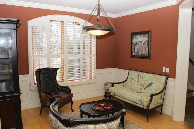 living area featuring plenty of natural light, ornamental molding, wainscoting, and wood finished floors