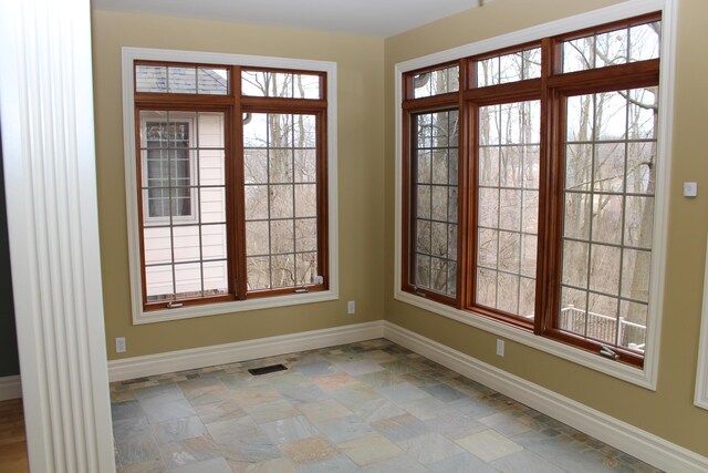 interior space featuring baseboards, stone finish floor, and visible vents