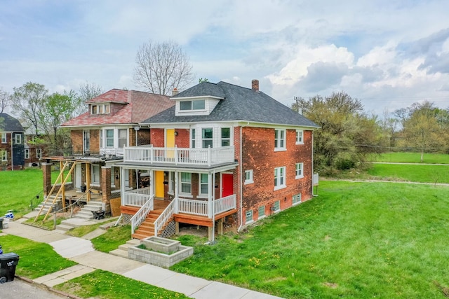 rear view of house with brick siding, a lawn, a balcony, and covered porch