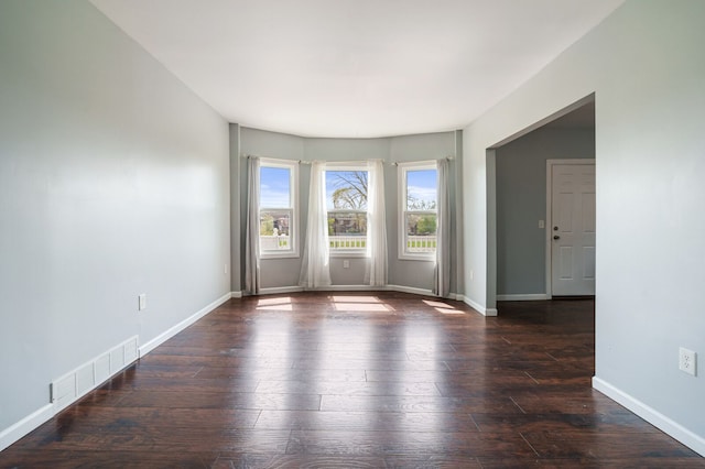 empty room featuring baseboards, visible vents, and hardwood / wood-style flooring