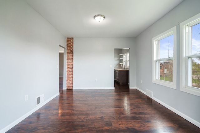 spare room featuring baseboards, visible vents, a sink, and dark wood-type flooring