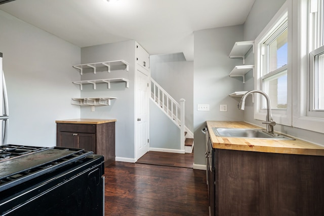 kitchen featuring dark brown cabinets, open shelves, a sink, wooden counters, and dark wood-type flooring