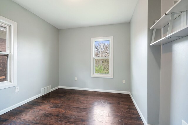 unfurnished room featuring baseboards, dark wood-type flooring, and visible vents