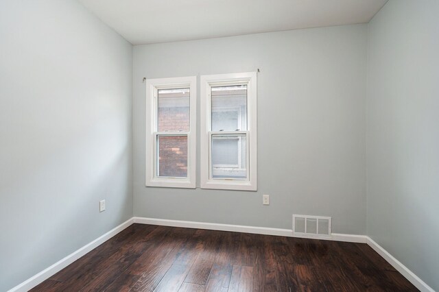 spare room featuring visible vents, dark wood finished floors, and baseboards