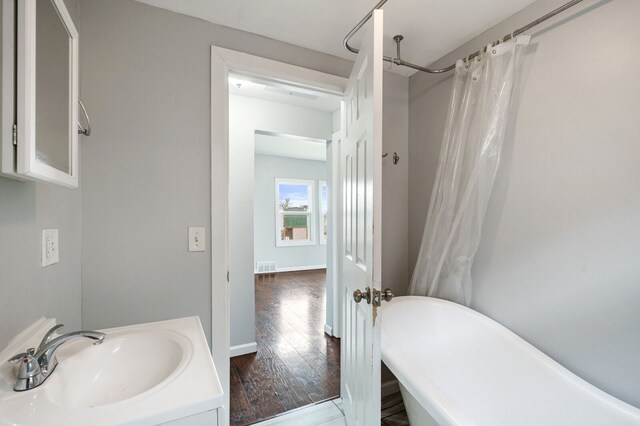 bathroom with visible vents, a freestanding bath, wood finished floors, vanity, and a shower with shower curtain