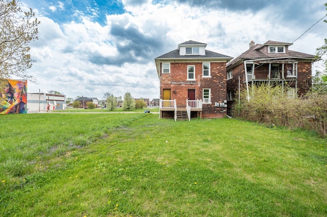 back of property featuring a lawn, a wooden deck, and brick siding