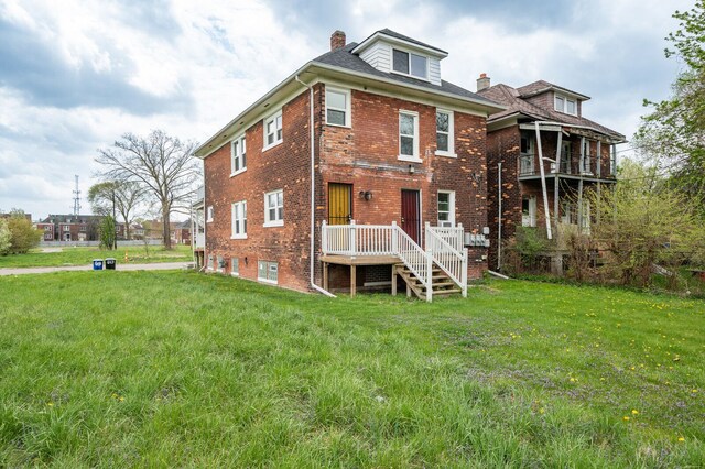 rear view of house with a lawn, brick siding, and a chimney