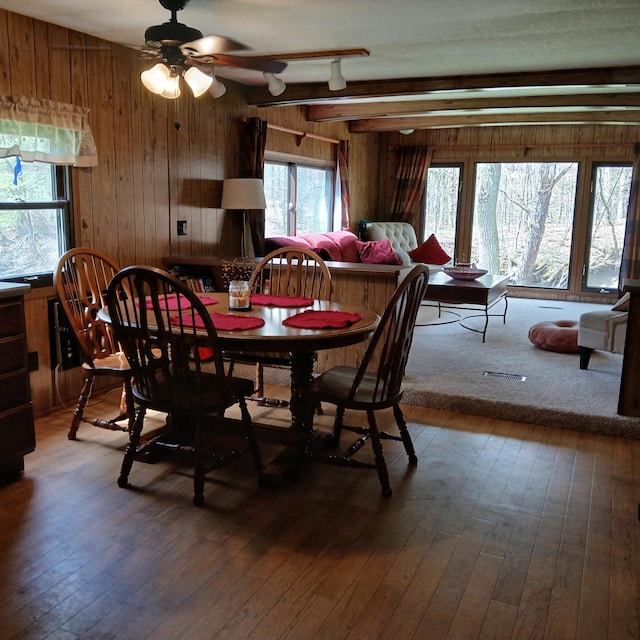 dining space featuring wood-type flooring, ceiling fan, and wood walls