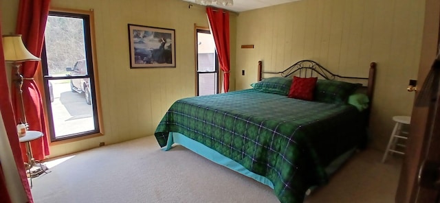 bedroom with carpet flooring and wood walls