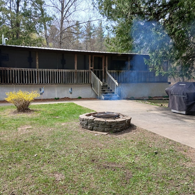 rear view of house with a lawn and a fire pit