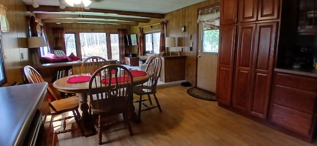 dining space with ceiling fan, light wood-type flooring, and beam ceiling