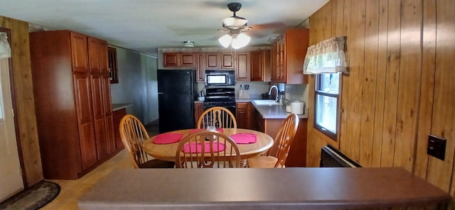 kitchen featuring a sink, brown cabinetry, black appliances, and wood walls