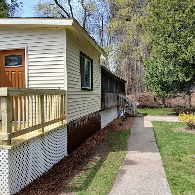 view of side of property with a wooden deck and a yard