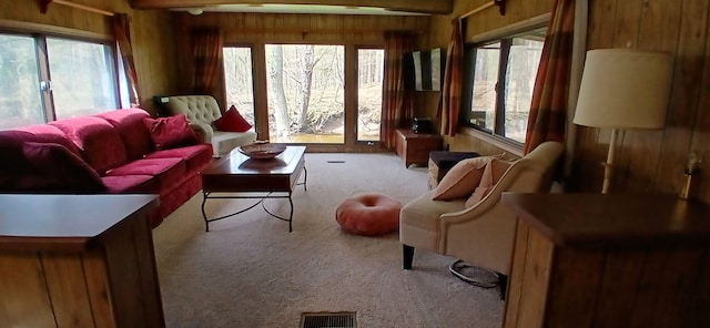 living room with wood walls, visible vents, plenty of natural light, and carpet