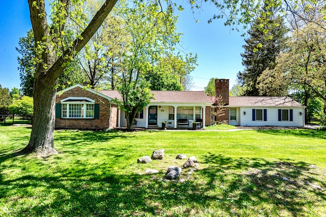 view of front of house featuring a chimney, a front yard, and brick siding