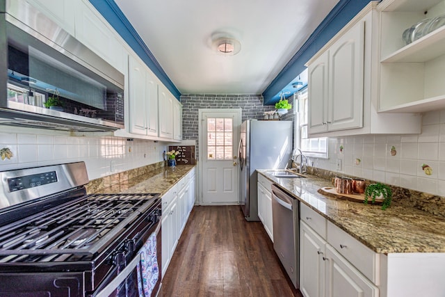 kitchen with appliances with stainless steel finishes, a sink, dark wood-style flooring, white cabinetry, and tasteful backsplash