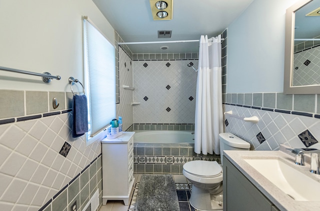 full bathroom featuring tile walls, tile patterned floors, tiled shower / bath, toilet, and vanity
