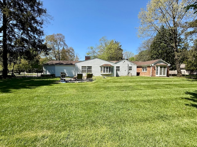 rear view of property featuring a yard and a chimney