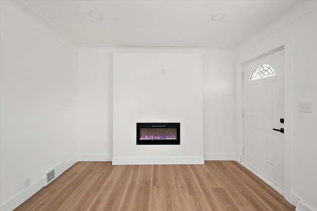 20040 E 8 Mile Rd, Harper Woods, MI 48225 - foyer entrance with light wood finished floors, a glass covered fireplace, and baseboards